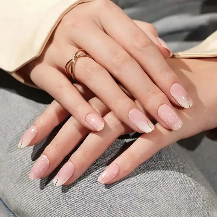 Blush pink almond nails with glitter speckles and delicate gold curving lines