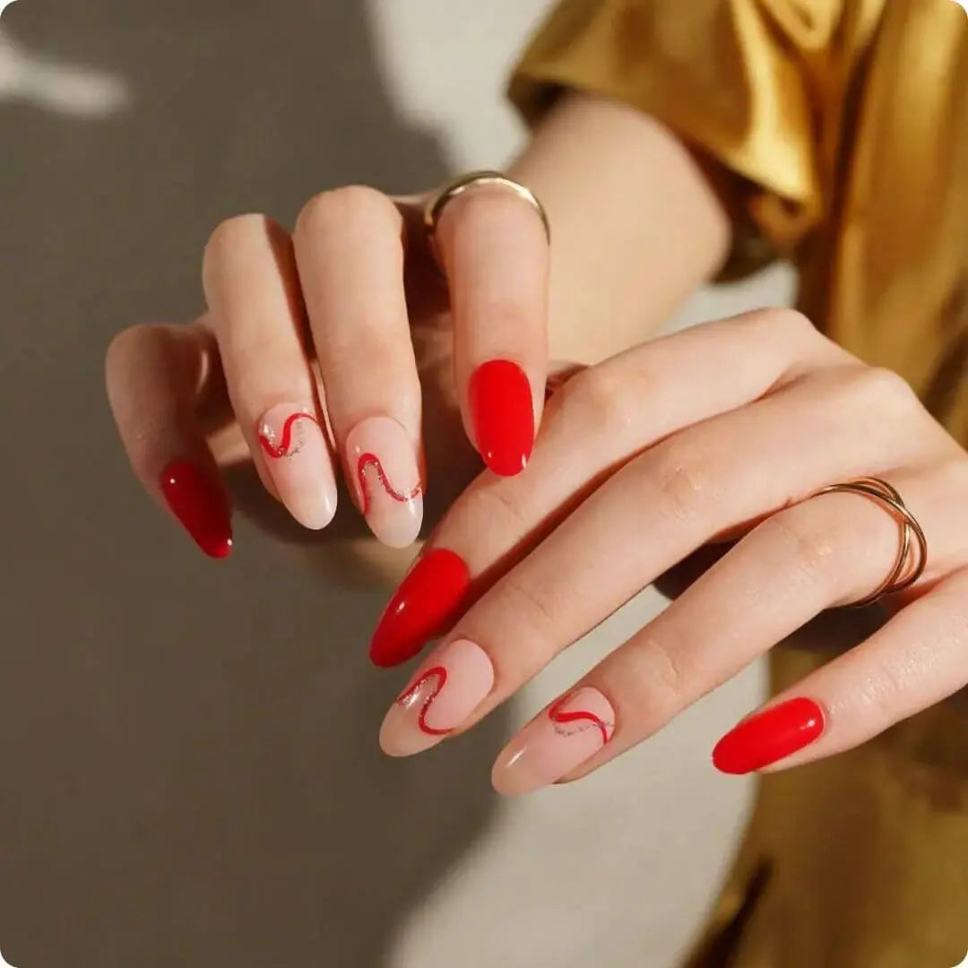 Long nude nails with glossy red wave swirls and some solid red accent nails.