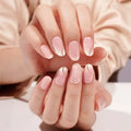 Short almond nails with pale pink base, glitter tips, and thin gold swirl lines