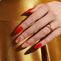 Red Waves nail set: nude base with red wave-style swirl accents, glossy finish.
