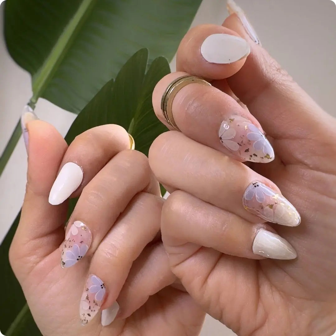 Petals nails on hands: sheer base with small floral motifs and plain matte white nails