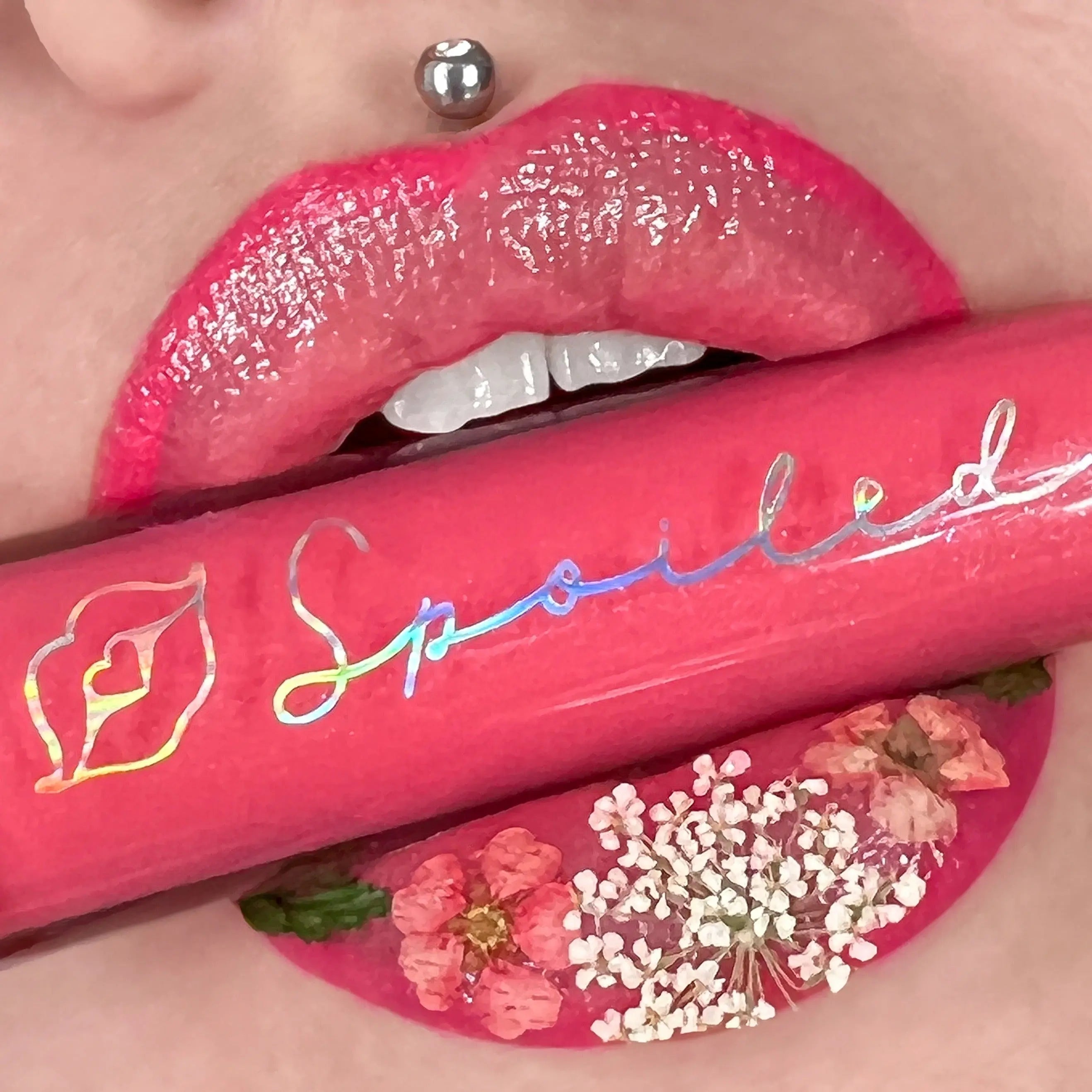Spoiled Lip Gloss in bright pink, on glossy lips with flower shimmer