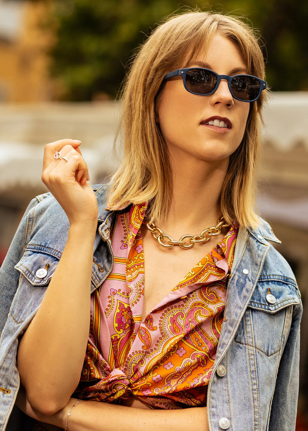 Sunglasses on face: Kara slate dark lenses, bold rectangular frame, woman wearing them