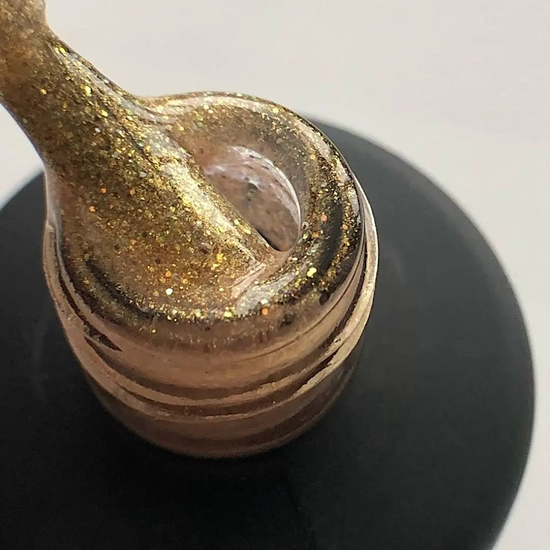 Close-up of gold-brown glitter gel on a curved nail