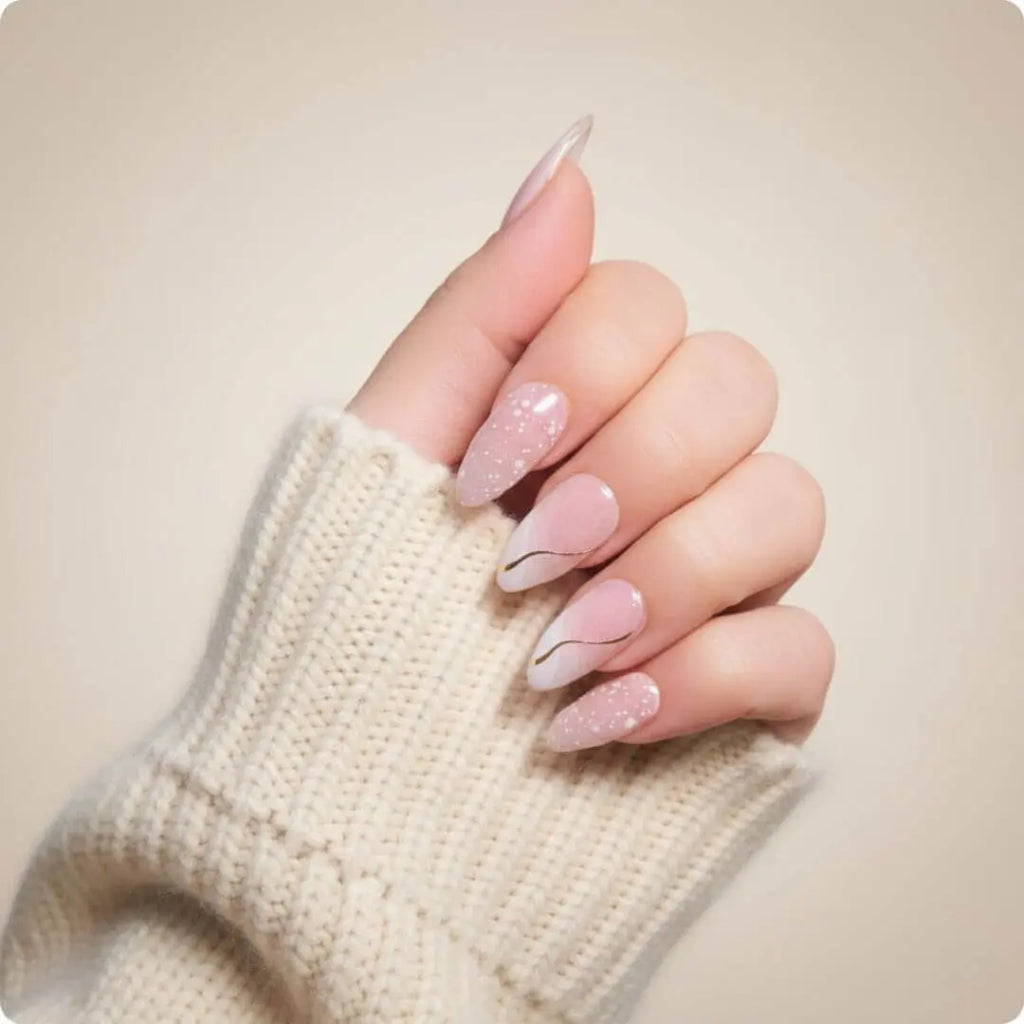 Almond nails with light pink shimmer, nude base, and thin gold half-moon accent