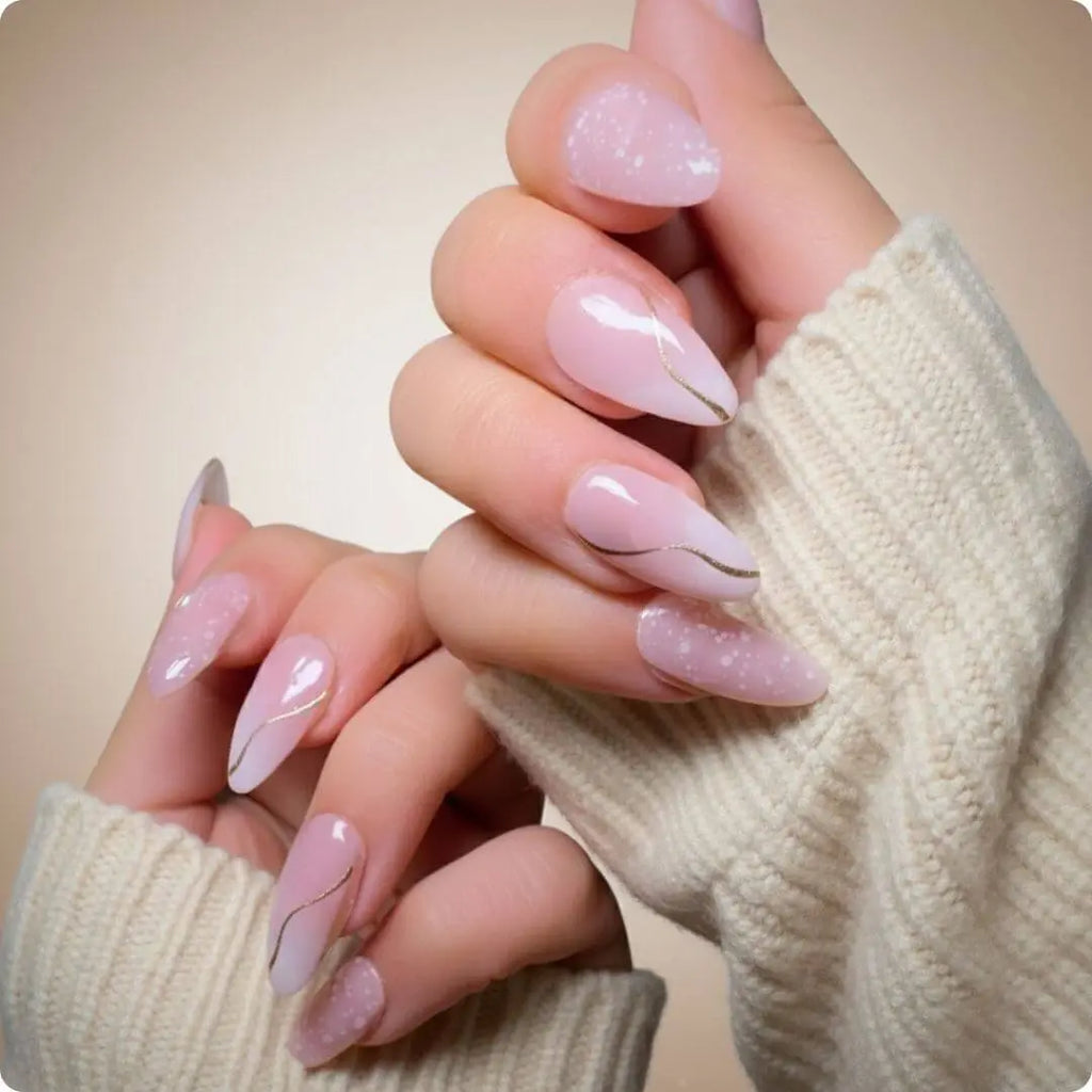 Close-up of almond nails in soft pink with glitter finish and delicate gold lines