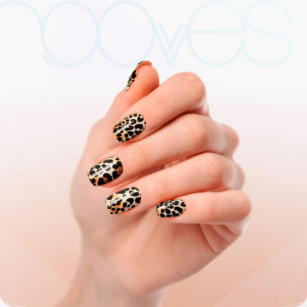 Leopard print nails on hand, almond tips with black, tan, and orange pattern