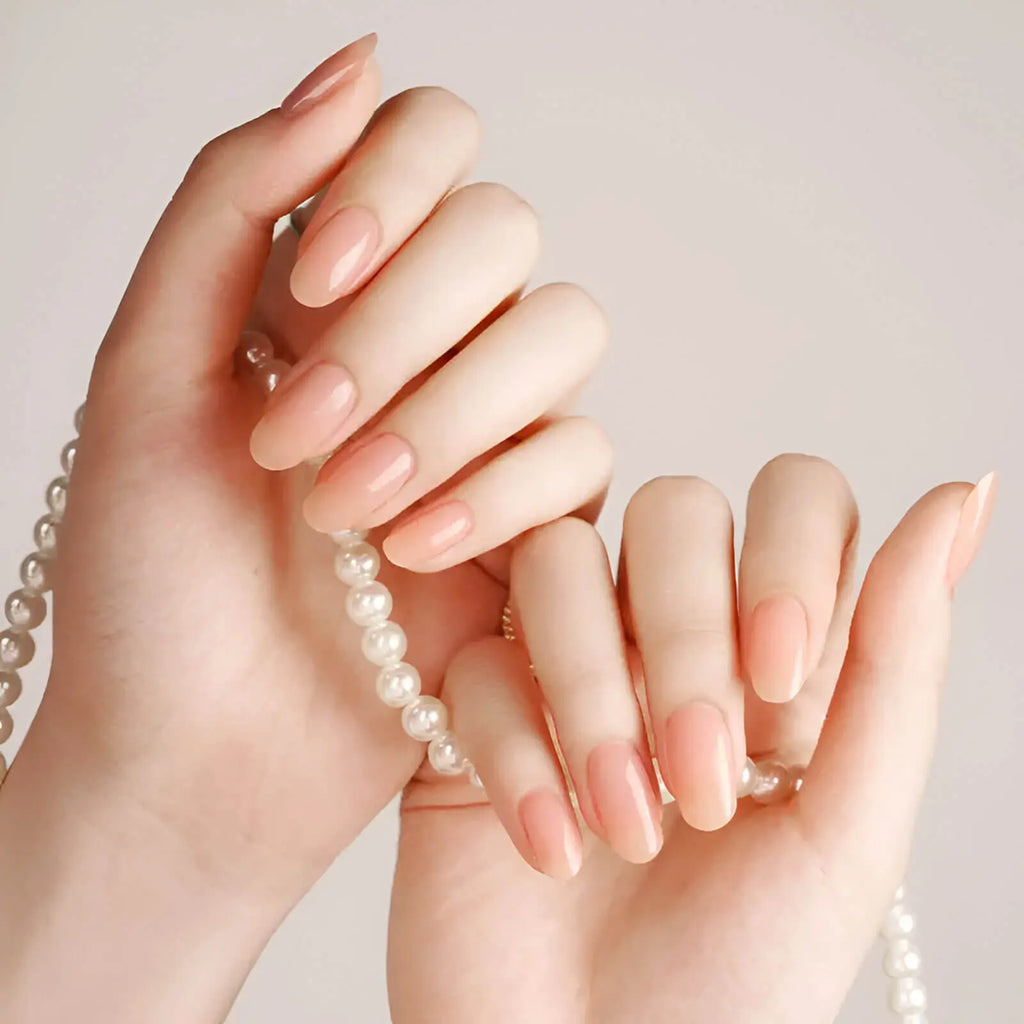 Natural nude gel nail strips on two hands, glossy short nails in a nude tone