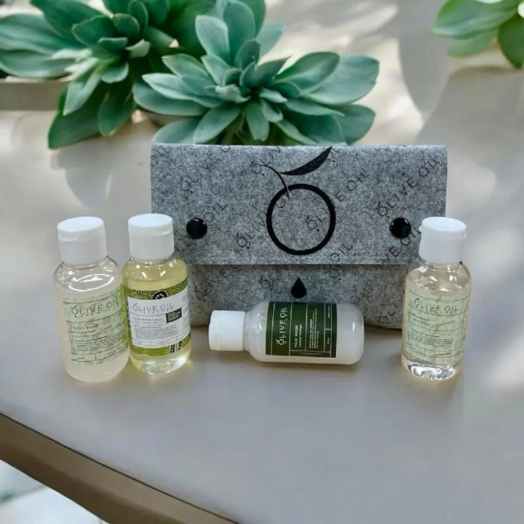 Gray felt case with four mini olive oil bottles and central green-label lotion tube