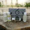 Sample pack with gray felt pouch and four olive oil skincare bottles plus lotion tube