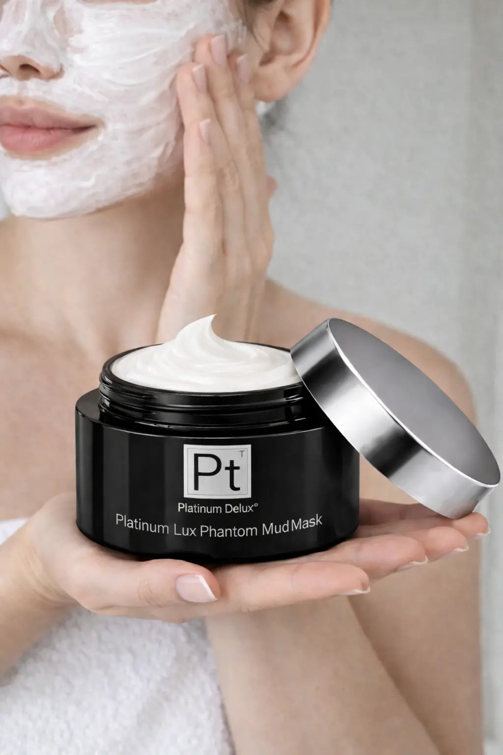 Platinum Lux Phantom Mud Mask jar held during application, white mask visible on skin