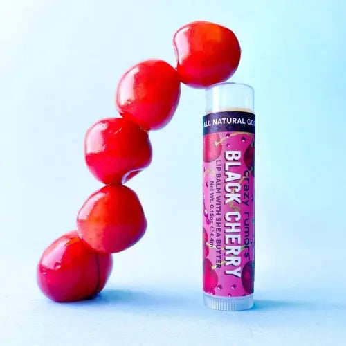 Black Cherry lip balm tube with a cluster of red cherries beside it