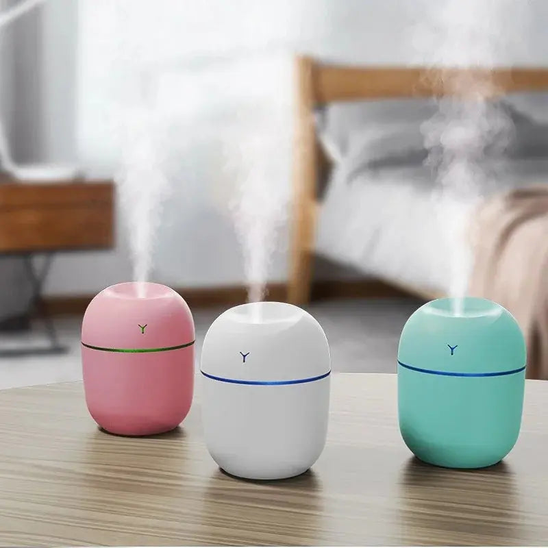 Portable ultrasonic humidifier aroma diffuser with LED, pink, white and teal.
