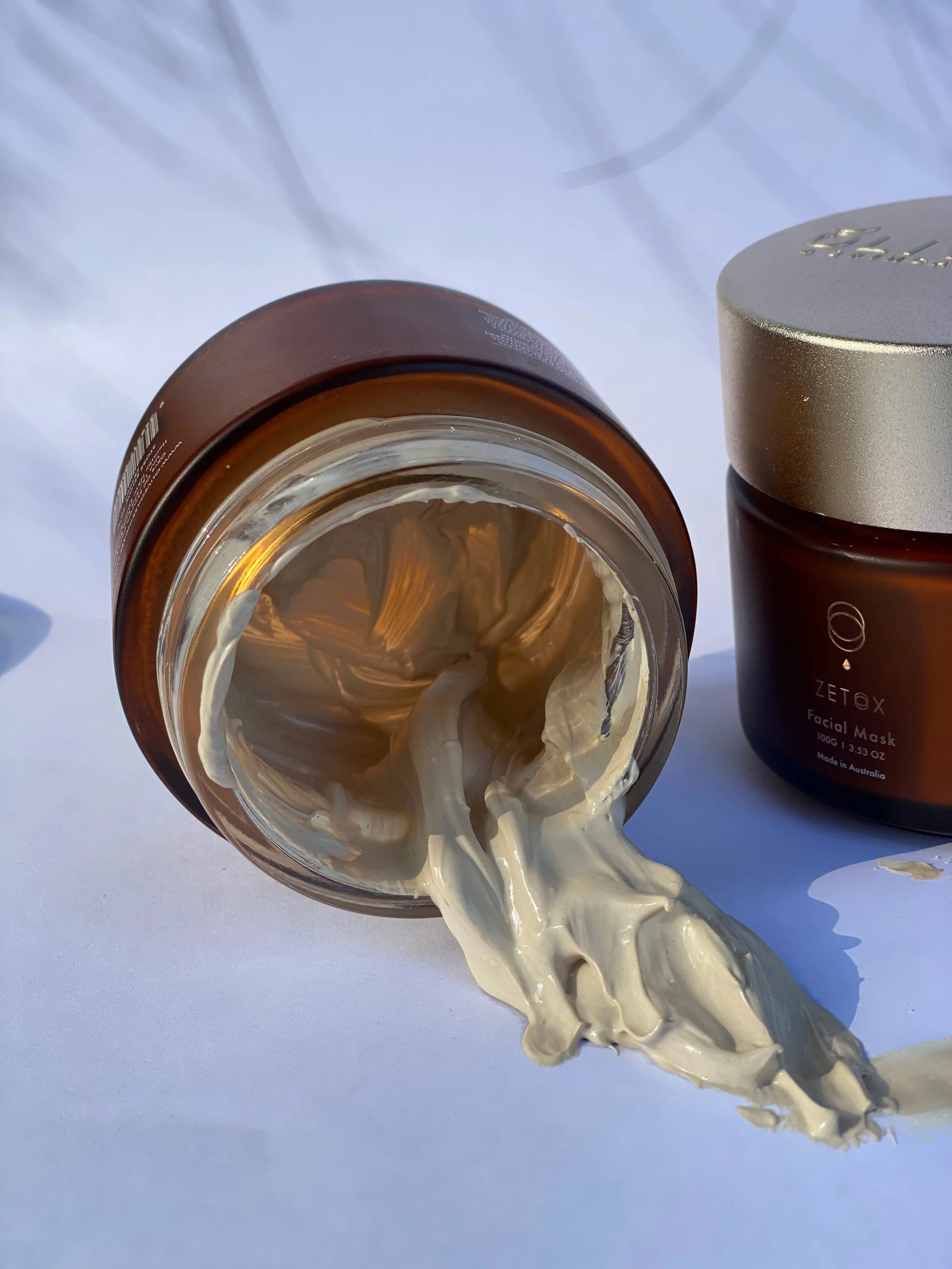 Sculpted clay mask paste scooped from jar, pale cream color