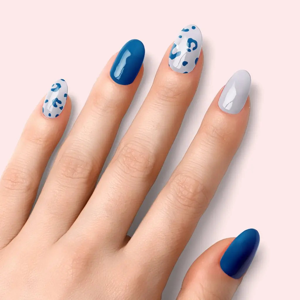 Blue leopard manicure: alternating deep-blue, pale-white, and leopard-print accent nails