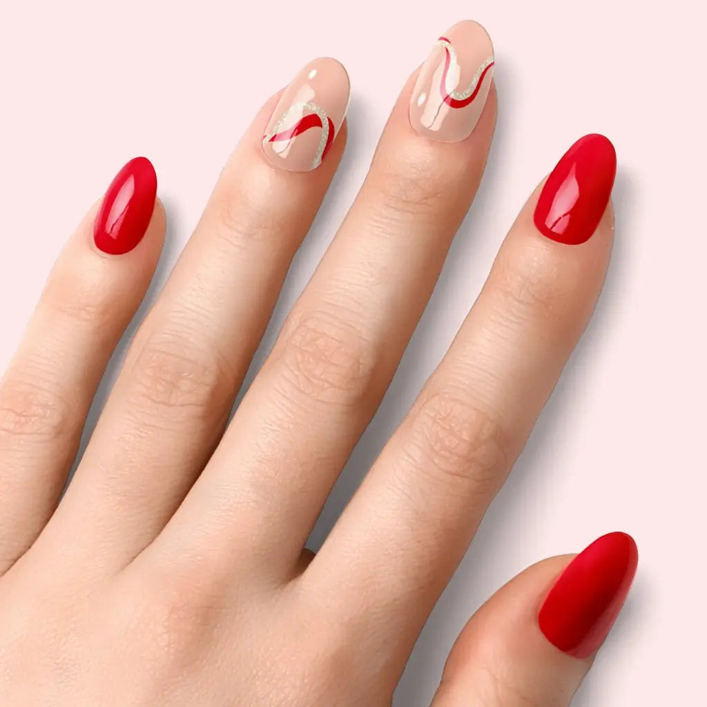 Red-and-nude wave nails: red solid tips with nude base and curved red swirl detail.