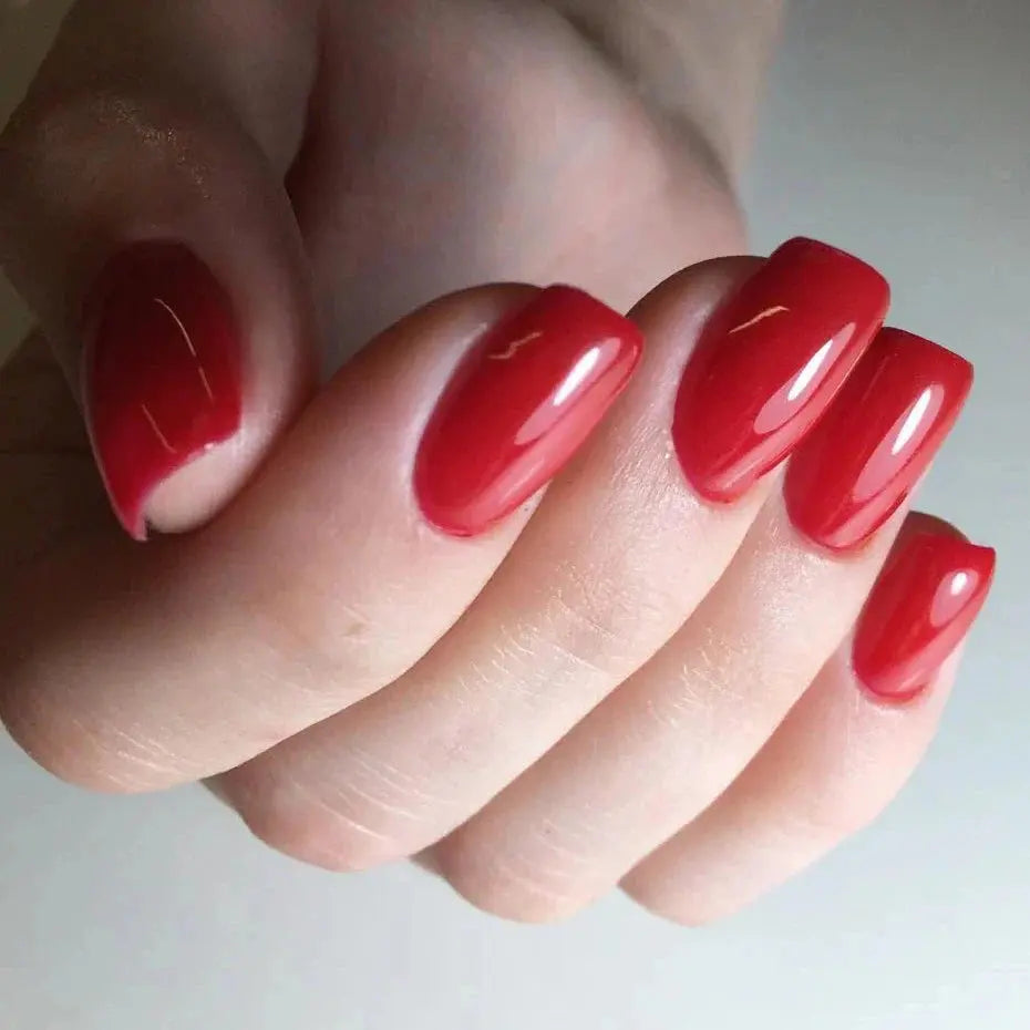 Glossy red nail polish on fingers, short oval nails