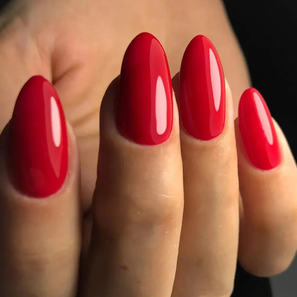 Deep red glossy nails on fingers, close-up oval shape